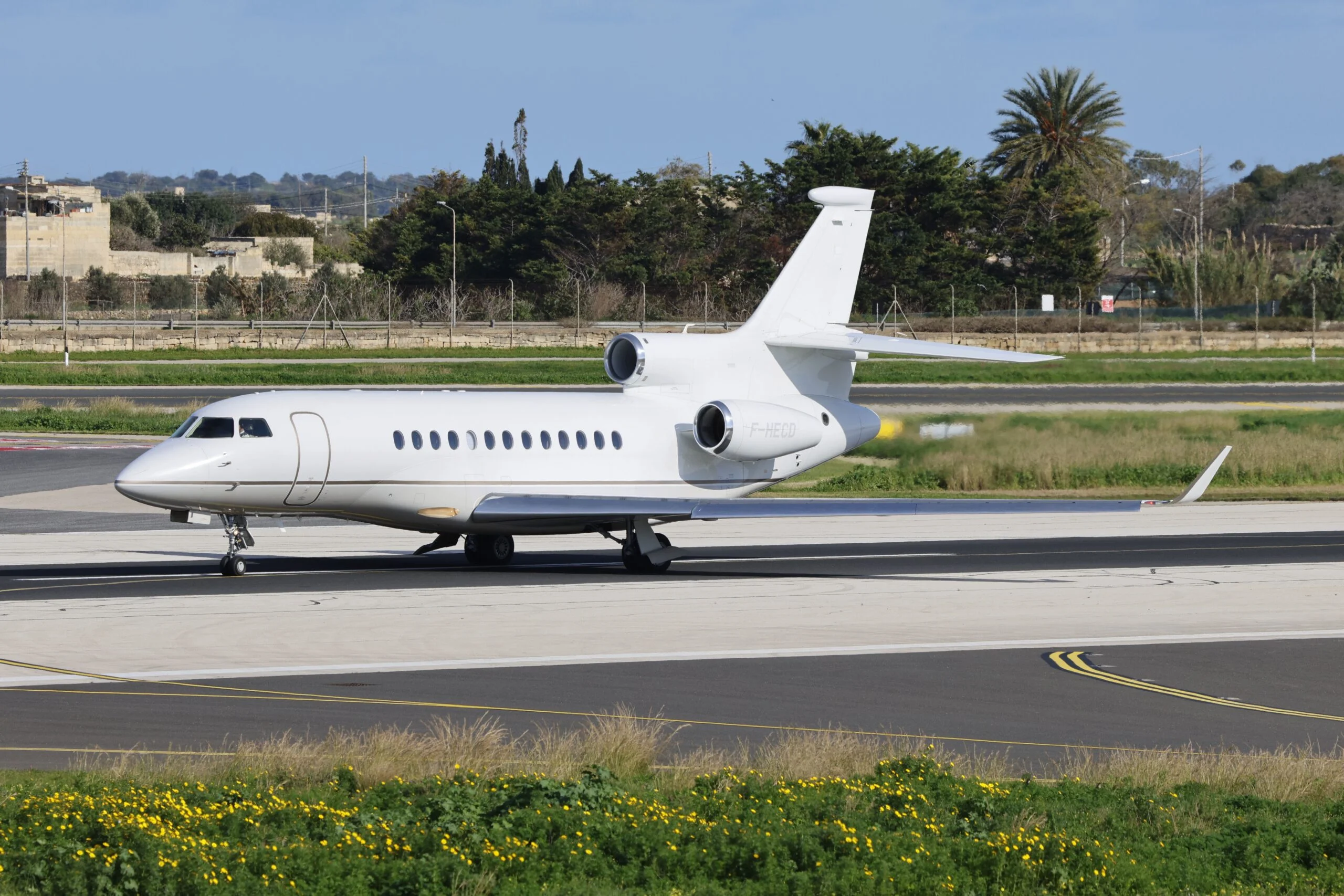 White Dassault Falcon 900 three-engine jet taxiing at an airport