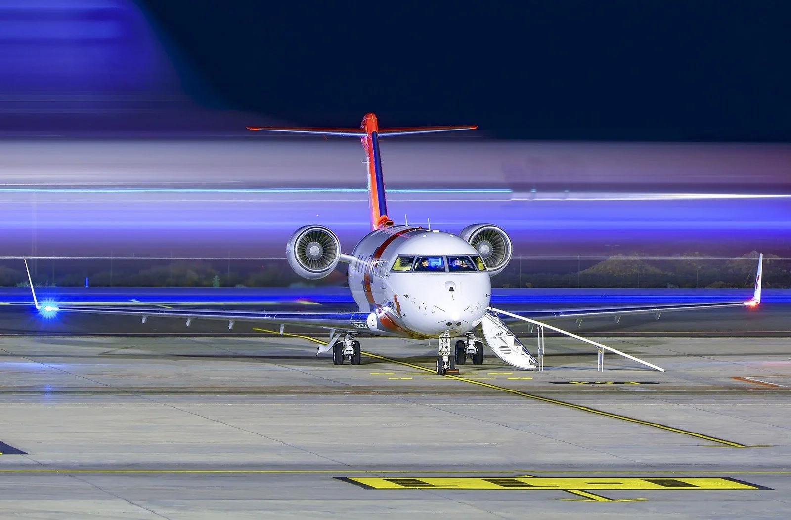 Bombardier Challenger 650 air ambulance jet on the apron at night, seen from the front with its steps down