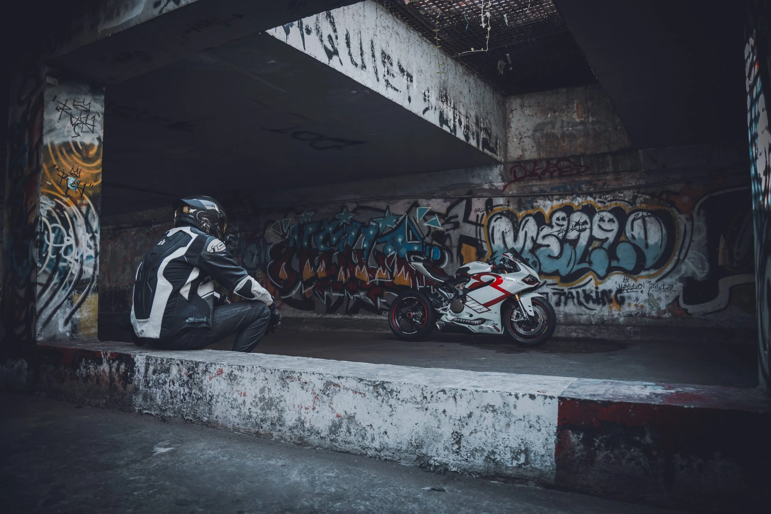 Motorcyclist in riding leathers and a helmet resting beside a sports motorcycle